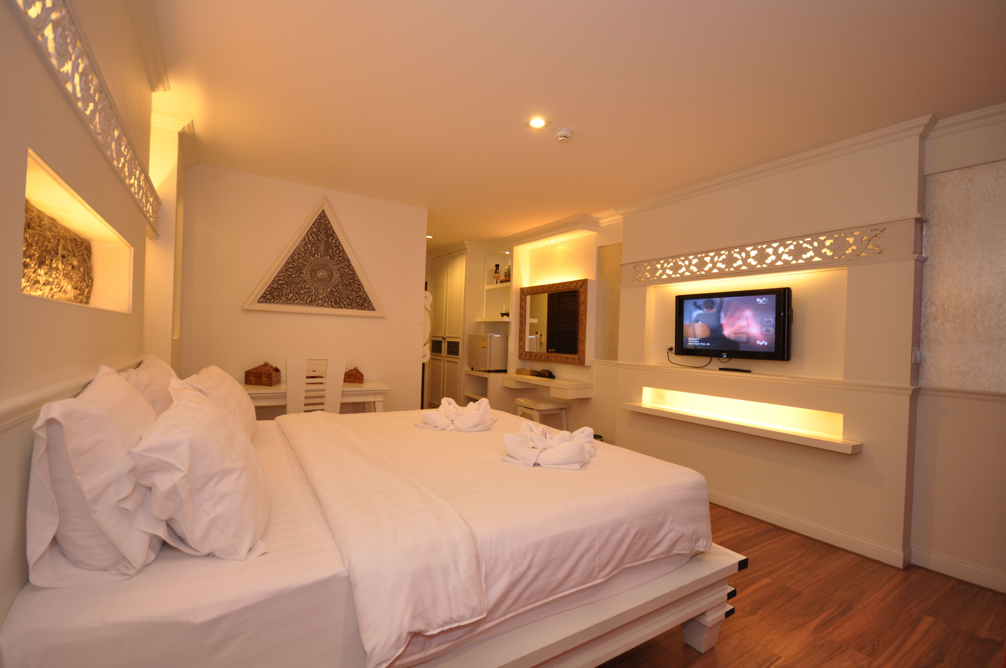 A hotel room with a large bed, a television mounted on the wall, and a bathroom visible in the background.