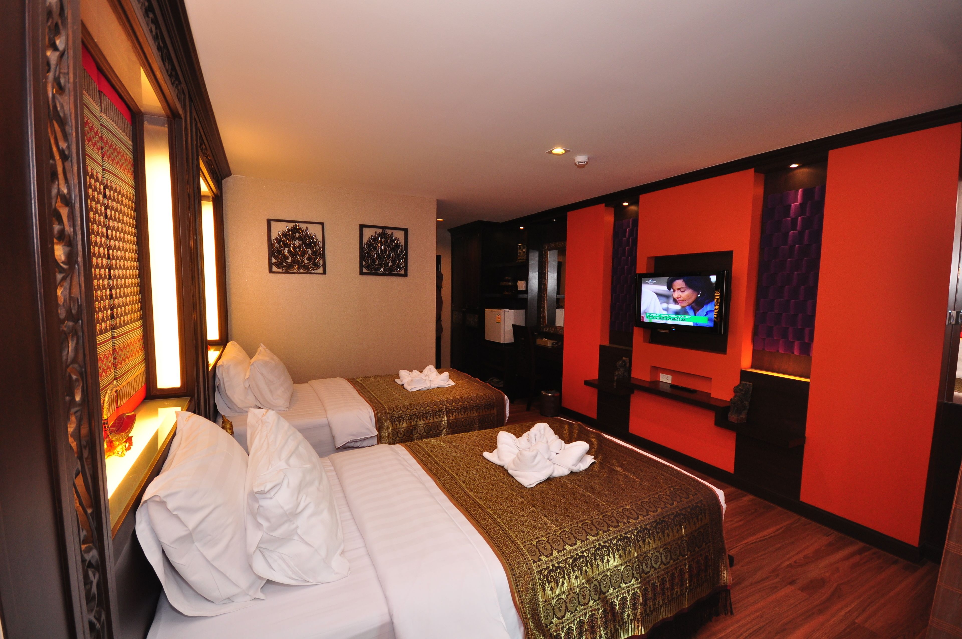A hotel room with two beds, a television, and a red accent wall.
