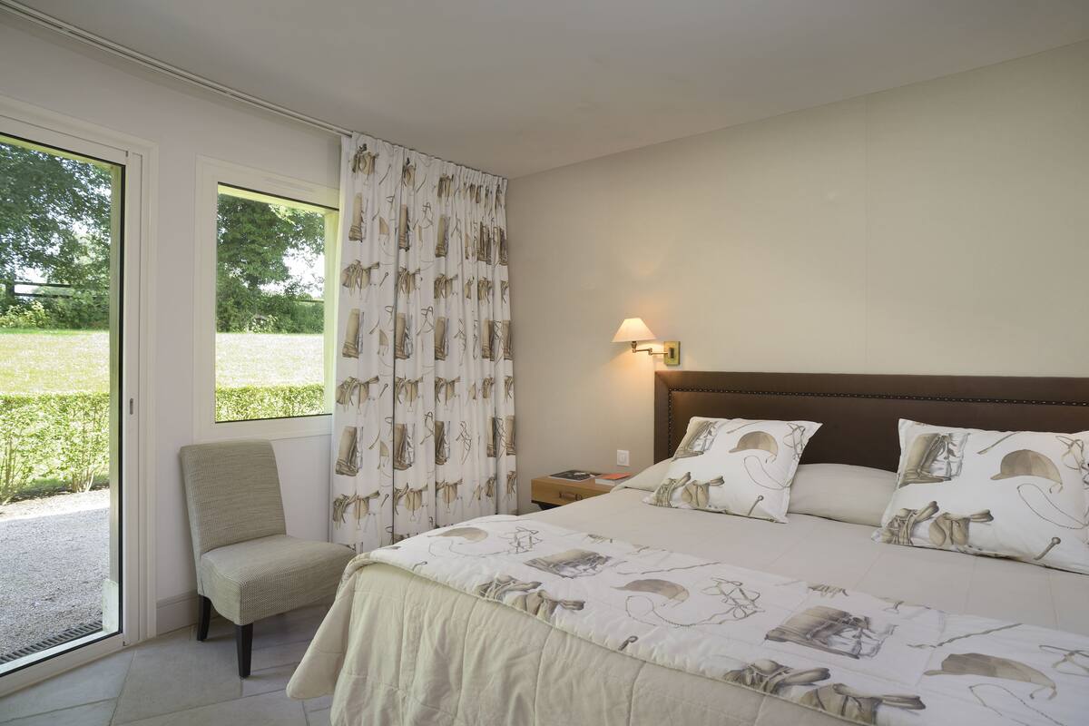 A bedroom with a bed, a chair, a nightstand, and a window with curtains.