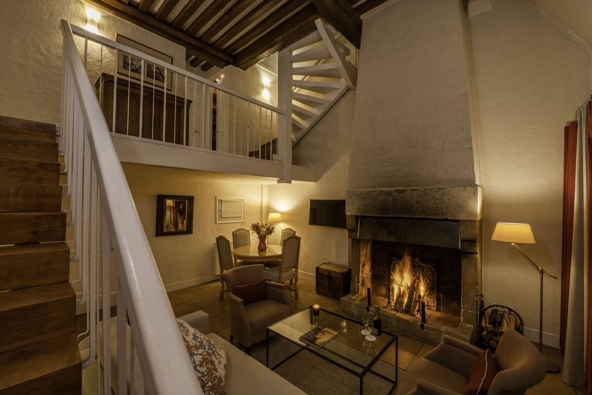 A cozy living room with a fireplace, comfortable seating, and a staircase leading to an upper level.