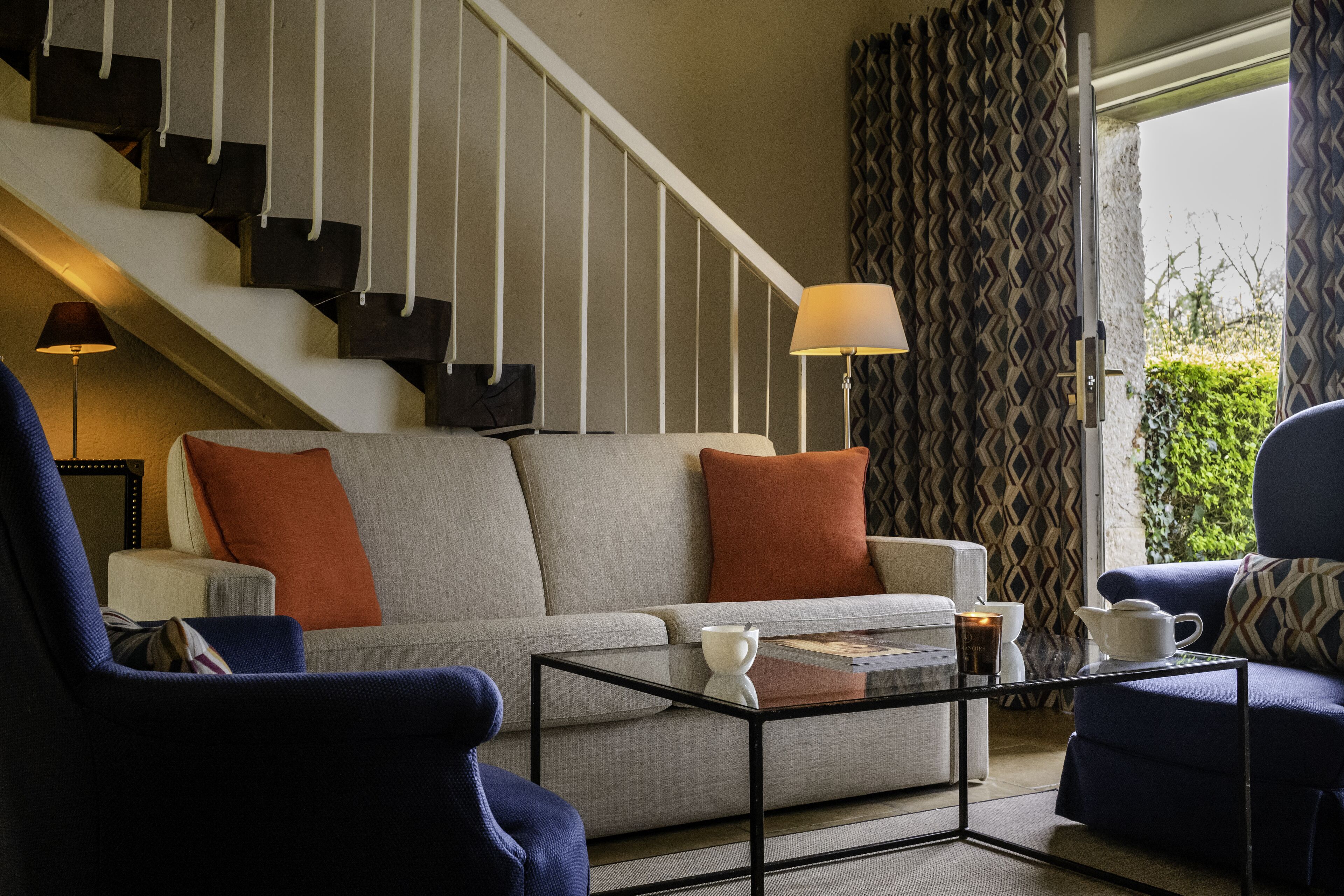 Ein Wohnzimmer mit einer Couch, Sesseln, einem Couchtisch und einer Treppe.