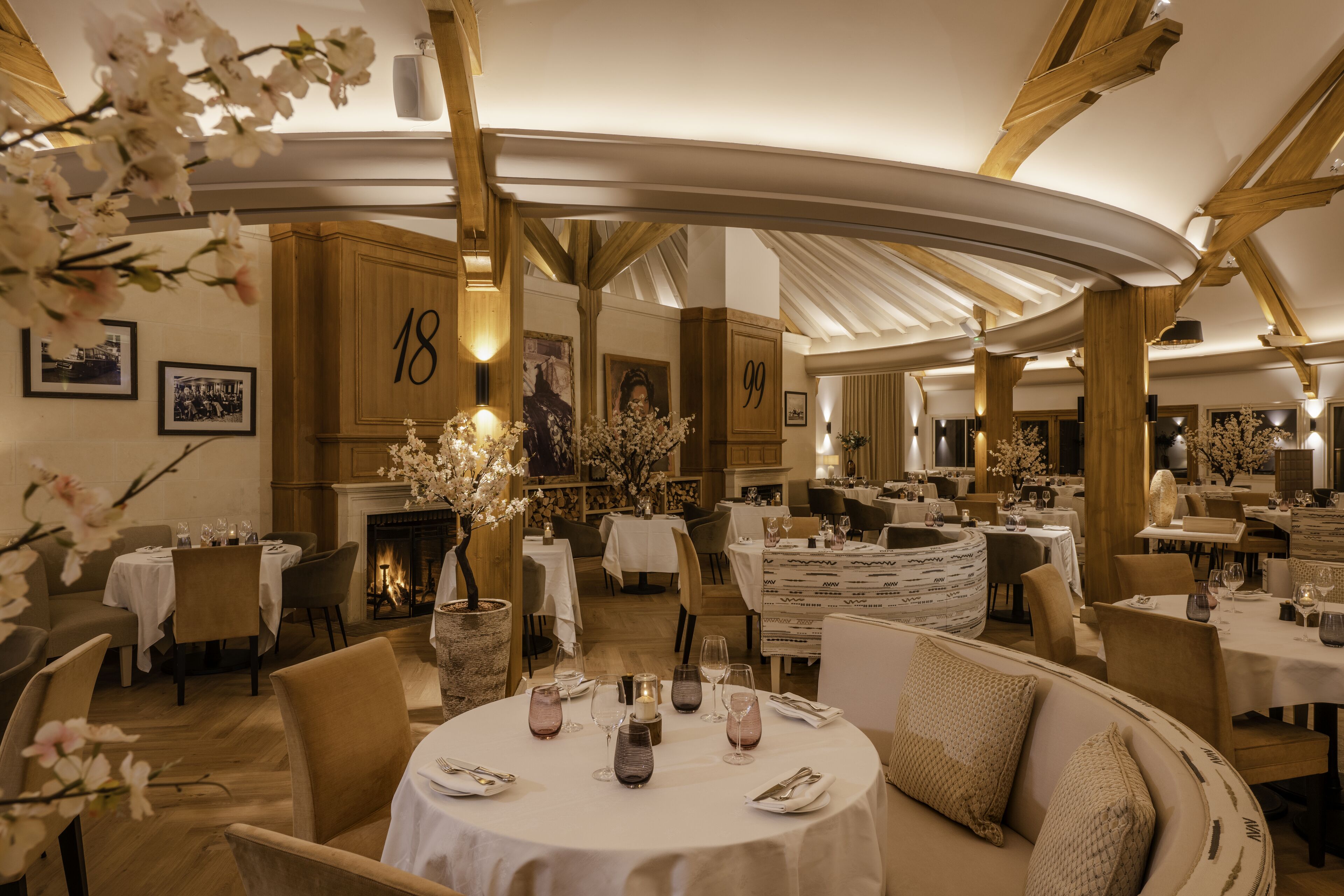 Un restaurante con mesas redondas, manteles blancos y un ambiente acogedor.