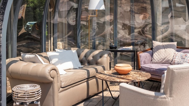 A conservatory with a glass ceiling, furnished with sofas and a round table, and a small stool. - Les Manoirs de Tourgéville (Tourgeville)