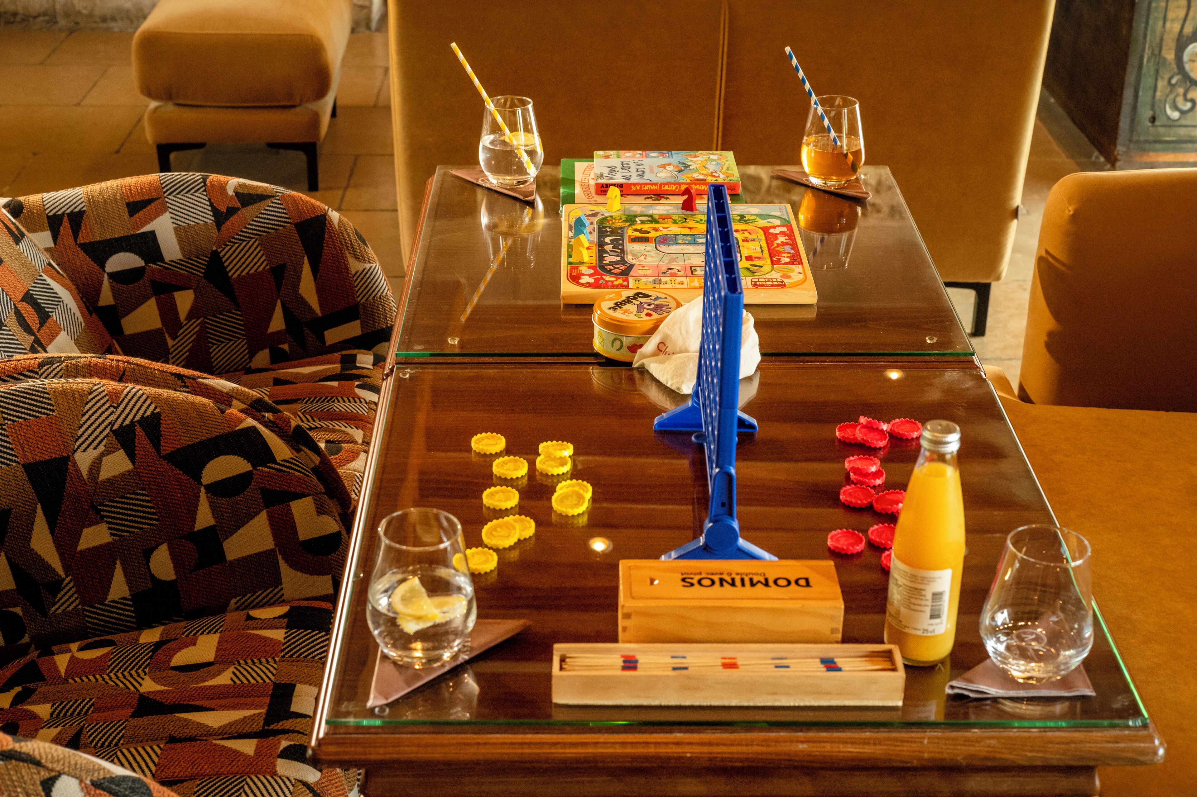 Una mesa de vidrio con un juego de mesa, bocadillos y bebidas.