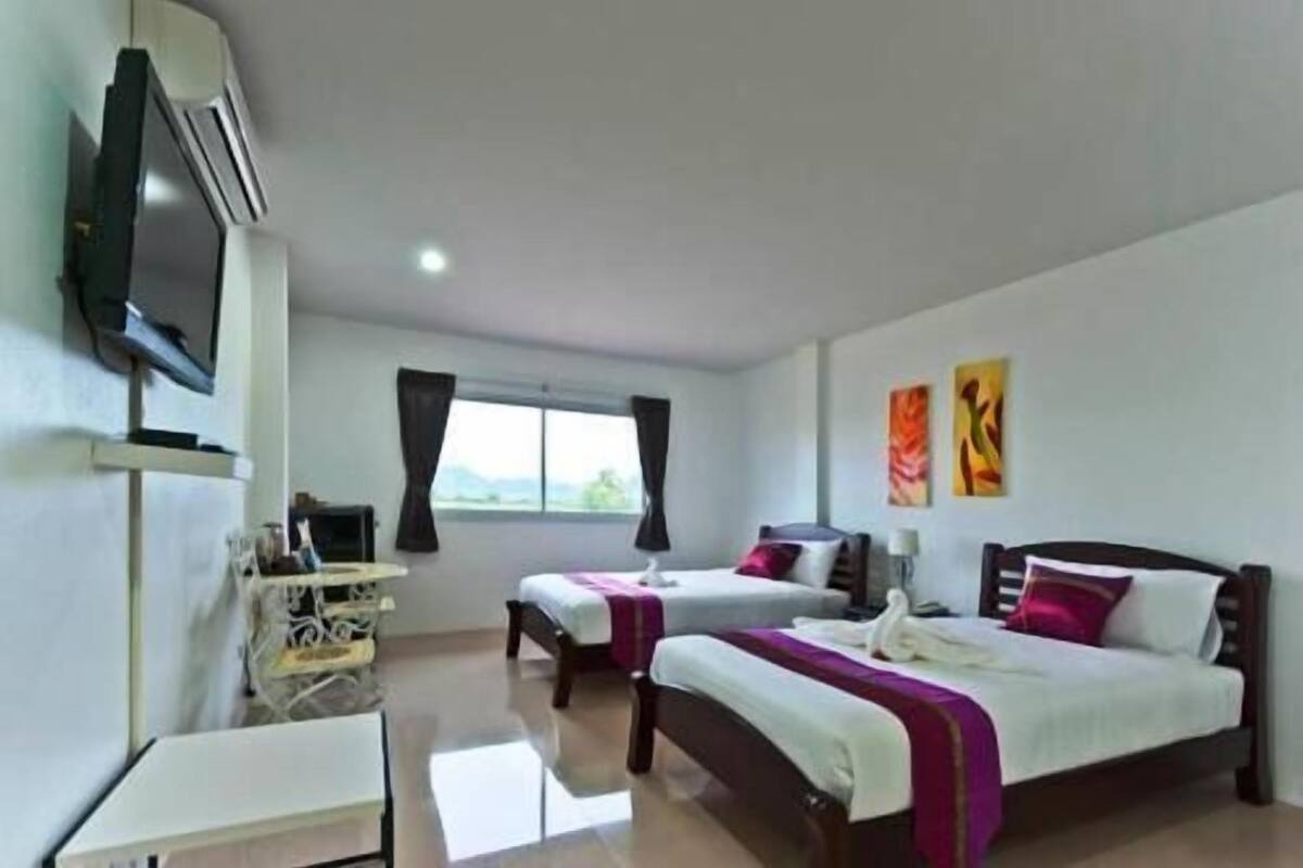 Habitación de hotel con dos camas, un escritorio, un televisor y obras de arte en las paredes.