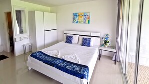 A modern bedroom with a large bed, white wardrobe, and a small table with a vase. - Phet Cha-am Plaza & Resort (Cha-am)