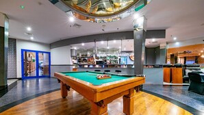 A pool table in a modern hotel lobby with a bar area in the background. - Hotel 500 Stryków (Strykow)