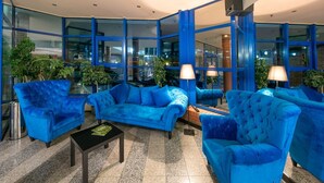 A lobby with blue upholstered sofas, a black coffee table, and floor lamps. - Hotel 500 Stryków (Strykow)