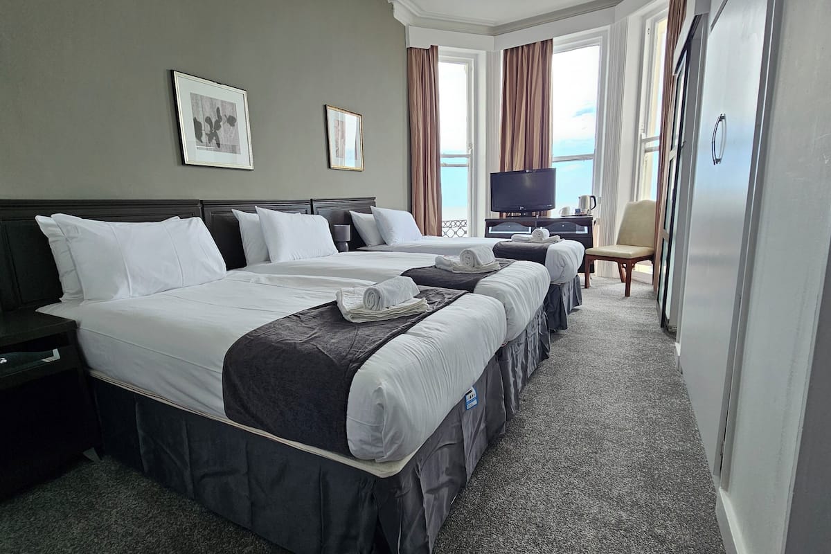 A hotel room with two beds, a TV, a desk, and a chair.