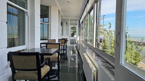 A corridor with a long table and chairs, large windows, and a view of the street. - The Strand Hotel (Eastbourne)