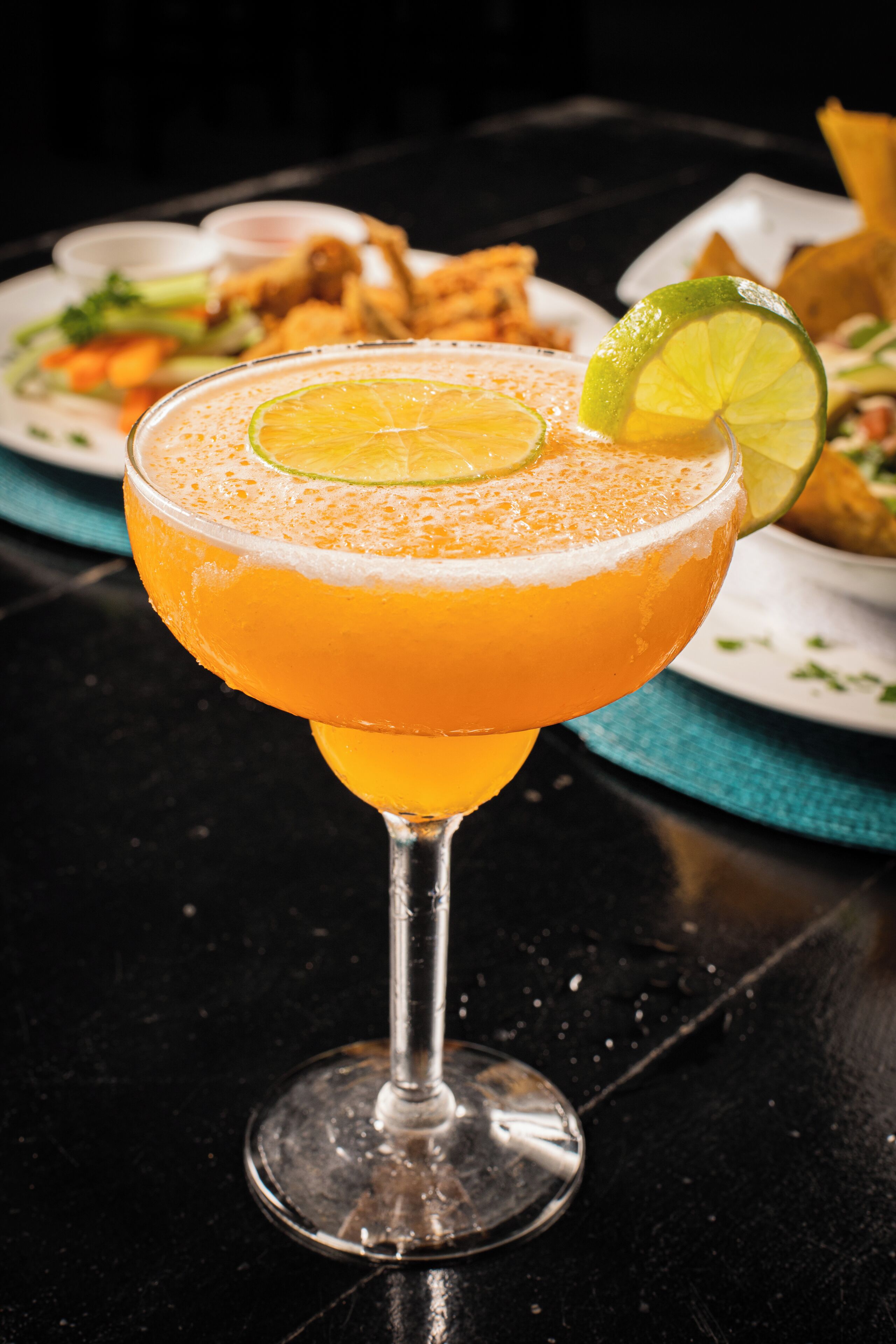 A cocktail with a lime garnish on a glass with a stem.
