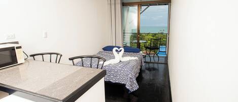 A hotel room with a bed, a desk, and a view of the ocean.