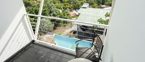 Un balcón con vista a una piscina, una silla y una mesa.