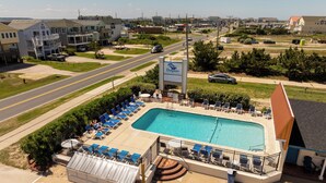 Una piscina con sillas de descanso, un puesto de socorrista y un cartel del Dolphin Inn.
