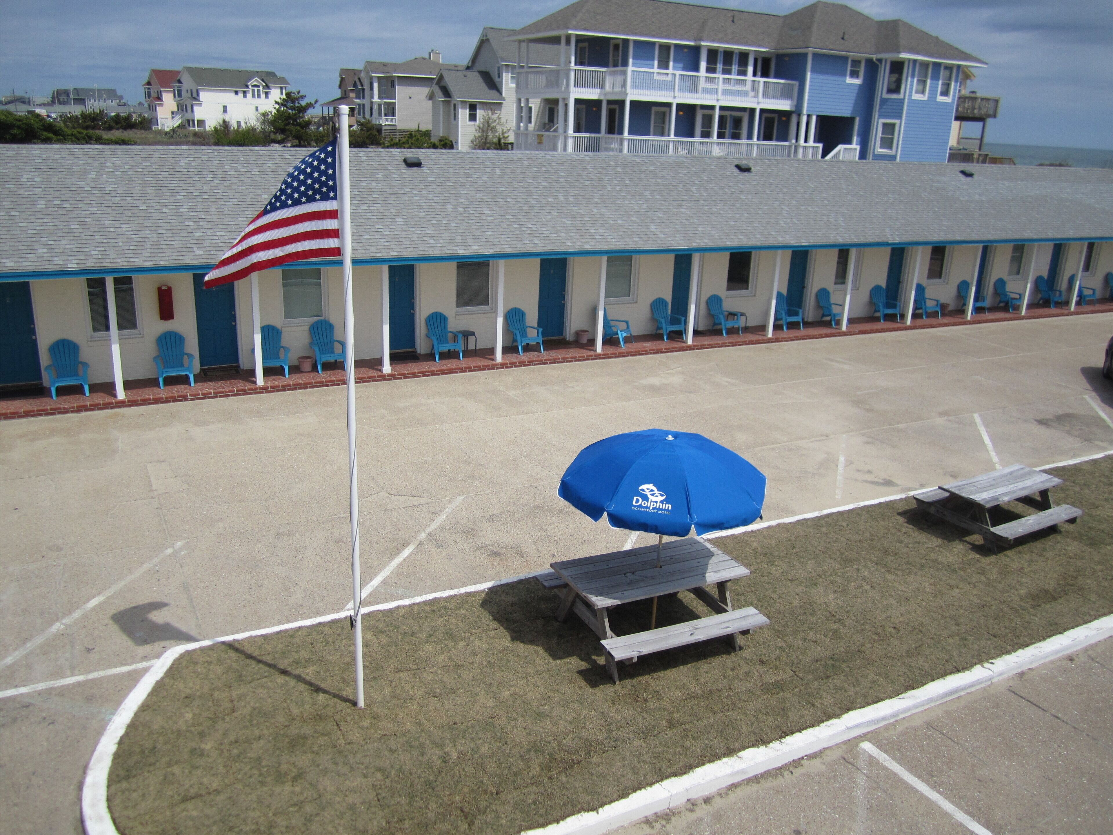 Un motel con una fila de sillas azules y un asta con la bandera estadounidense.