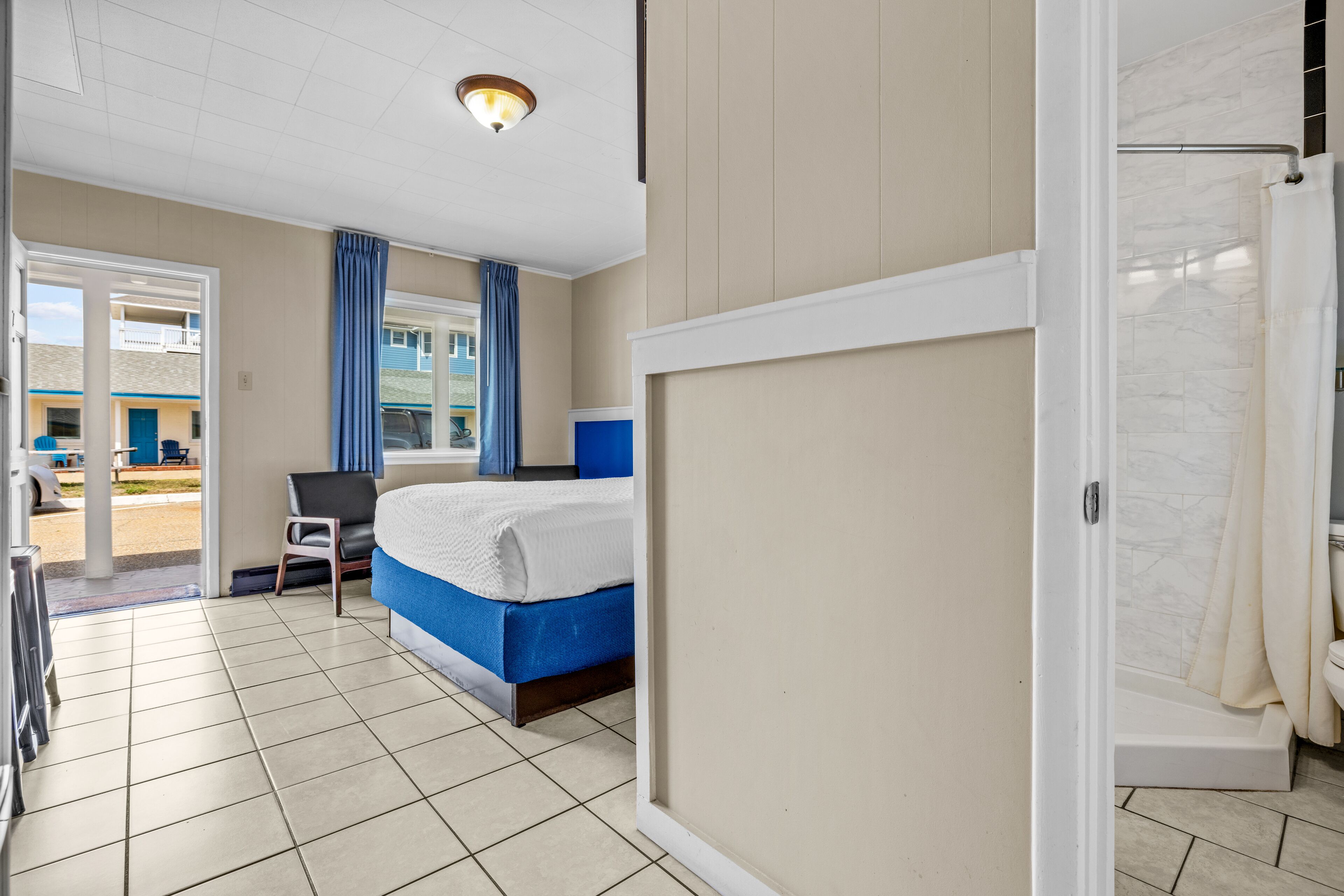 Une chambre d’hôtel avec un lit, une chaise, une douche et une vue sur l’extérieur.