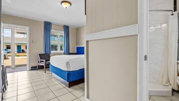 Une chambre d’hôtel avec un lit, une chaise, une douche et une vue sur l’extérieur.