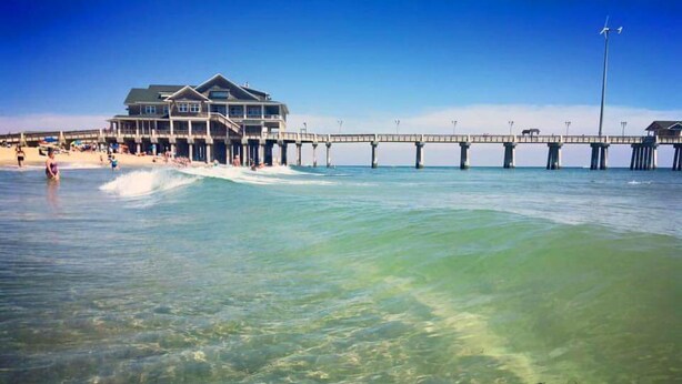 Una casa de playa con un muelle que se adentra en el océano.