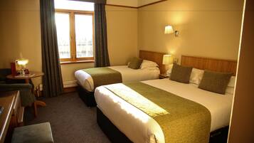A hotel room with two beds, a desk, and a window with curtains.
