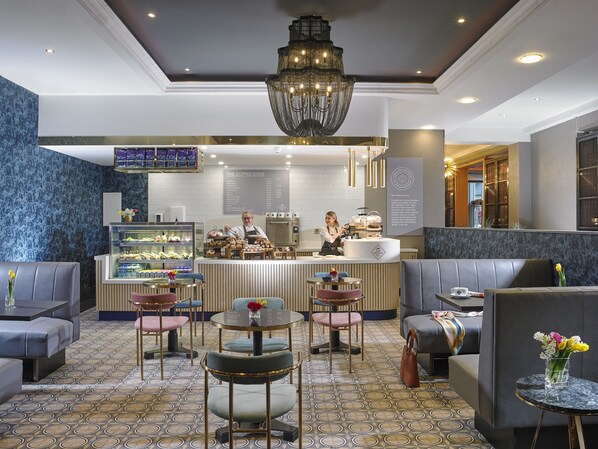 A modern coffee shop with a barista preparing drinks, seating areas, and a menu board.