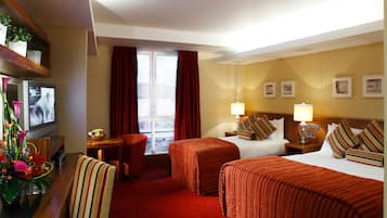 Habitación de hotel con dos camas, televisor, escritorio con computadora y ventana con cortinas.
