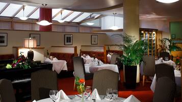 A restaurant with striped chairs, a piano, and a large potted plant.