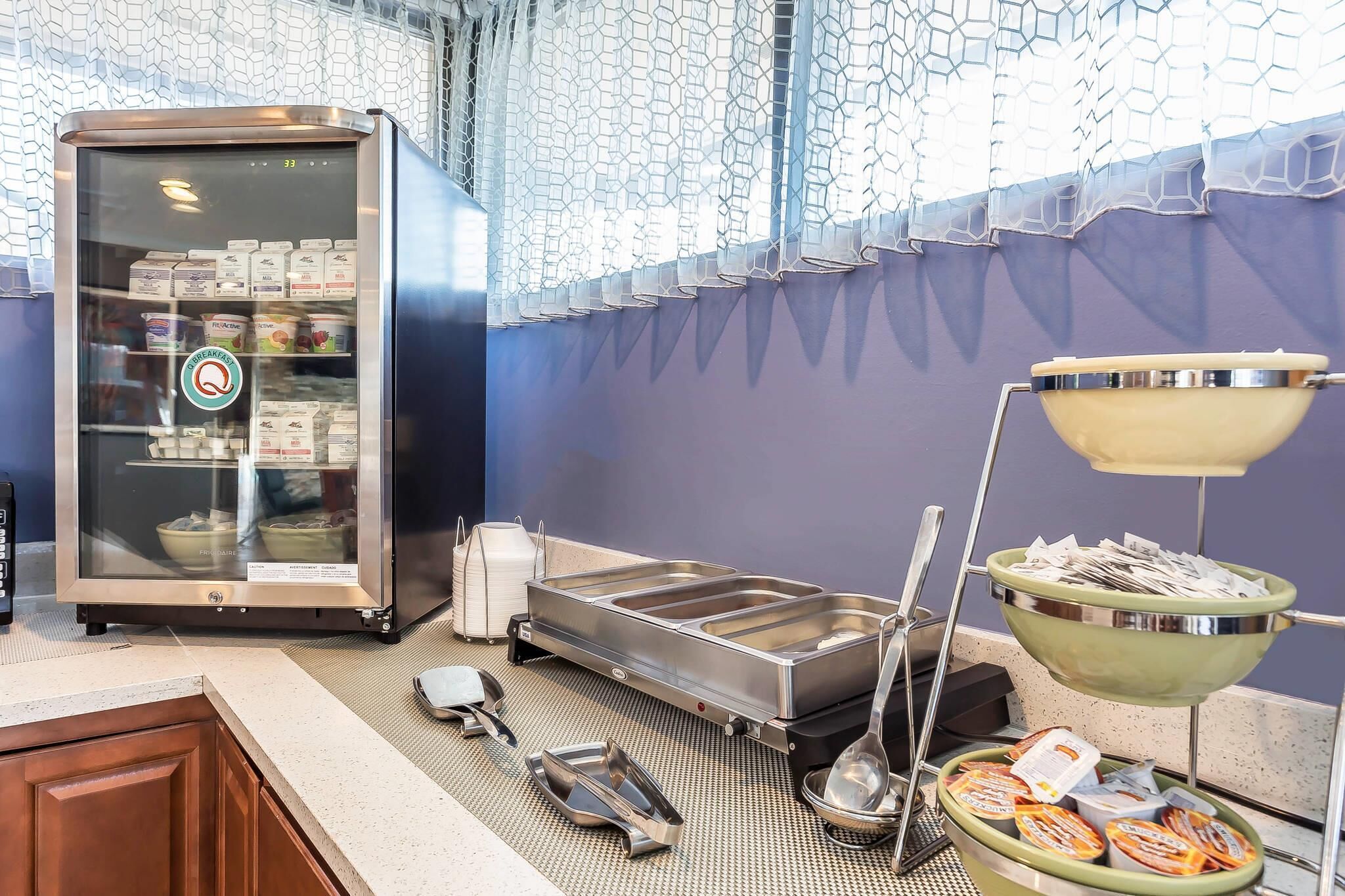 A buffet setup with a refrigerator, serving trays, and a bowl of condiments.