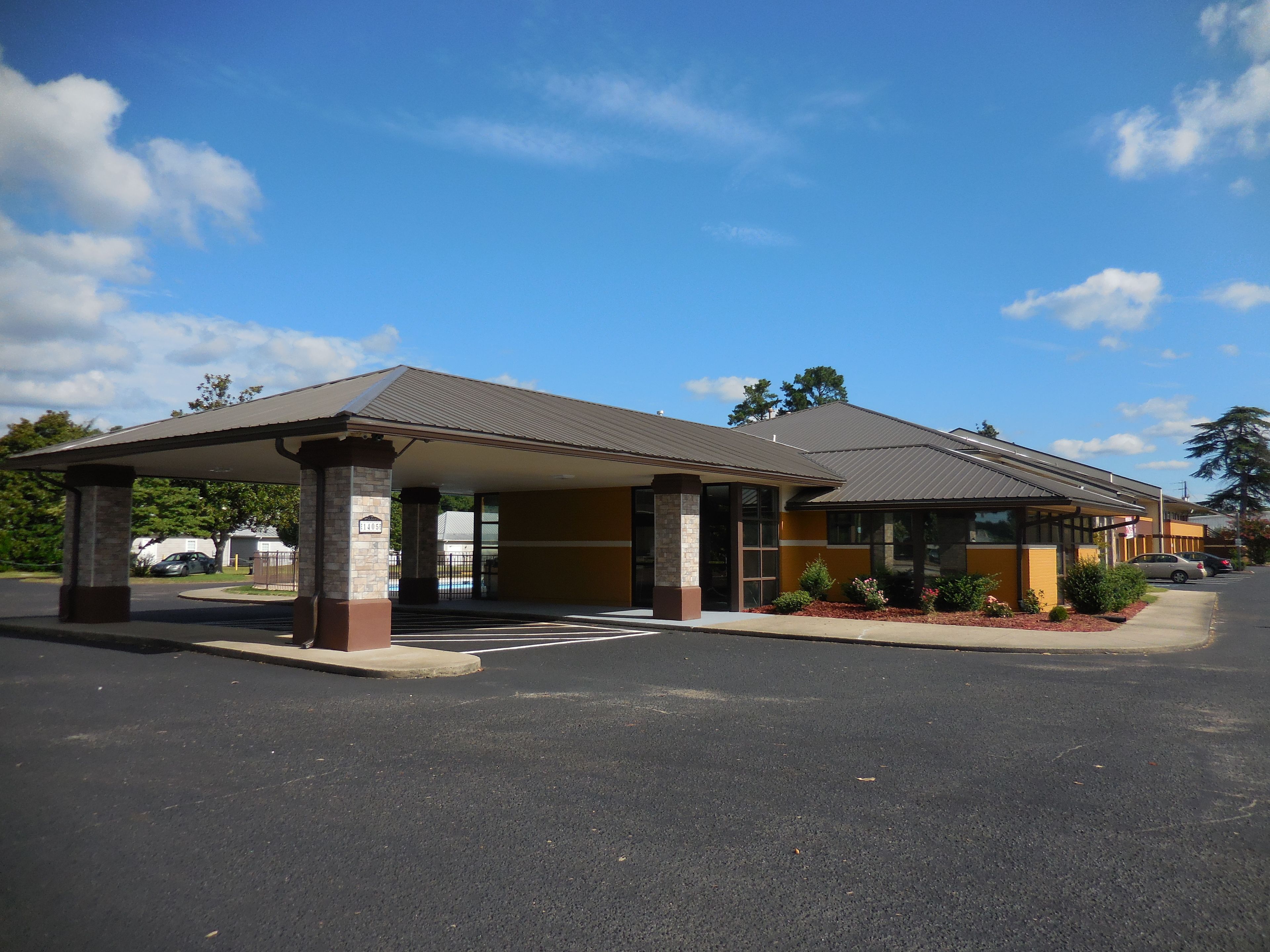 A motel with a covered parking area and a two-story building.
