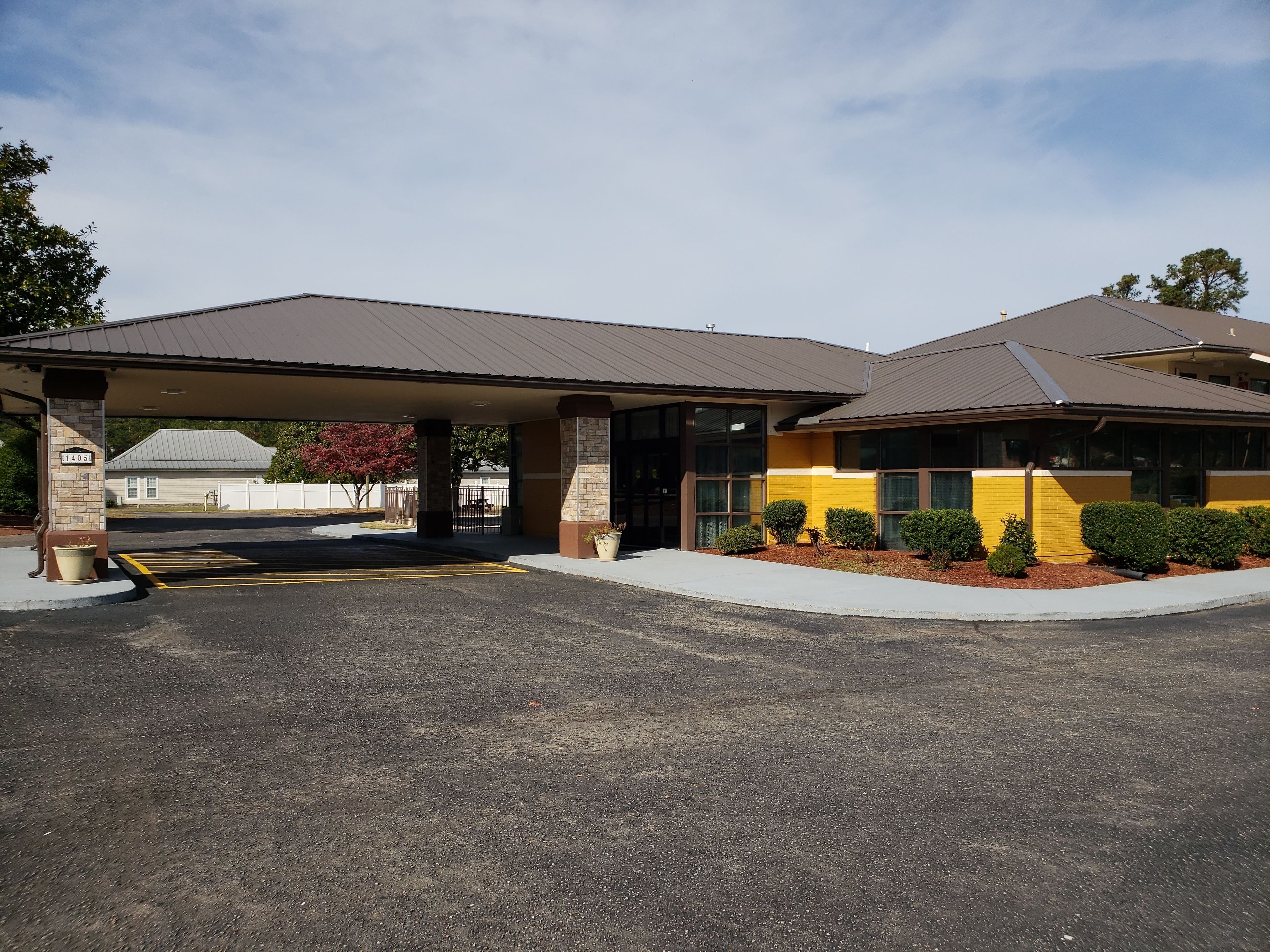 A building with a covered parking area and a yellow facade.