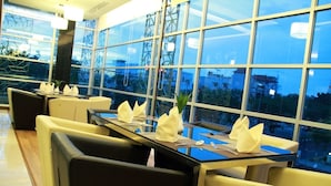 Un restaurant doté d’une longue table dressée pour le dîner, de grandes fenêtres et d’un décor intérieur moderne.