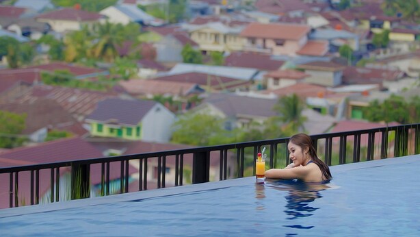 Une personne se détend dans une piscine, avec une vue sur le paysage urbain.