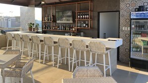 An outdoor bar area with wicker chairs and a bar counter stocked with bottles. - Apollonia Royale Hotel (Angeles City)