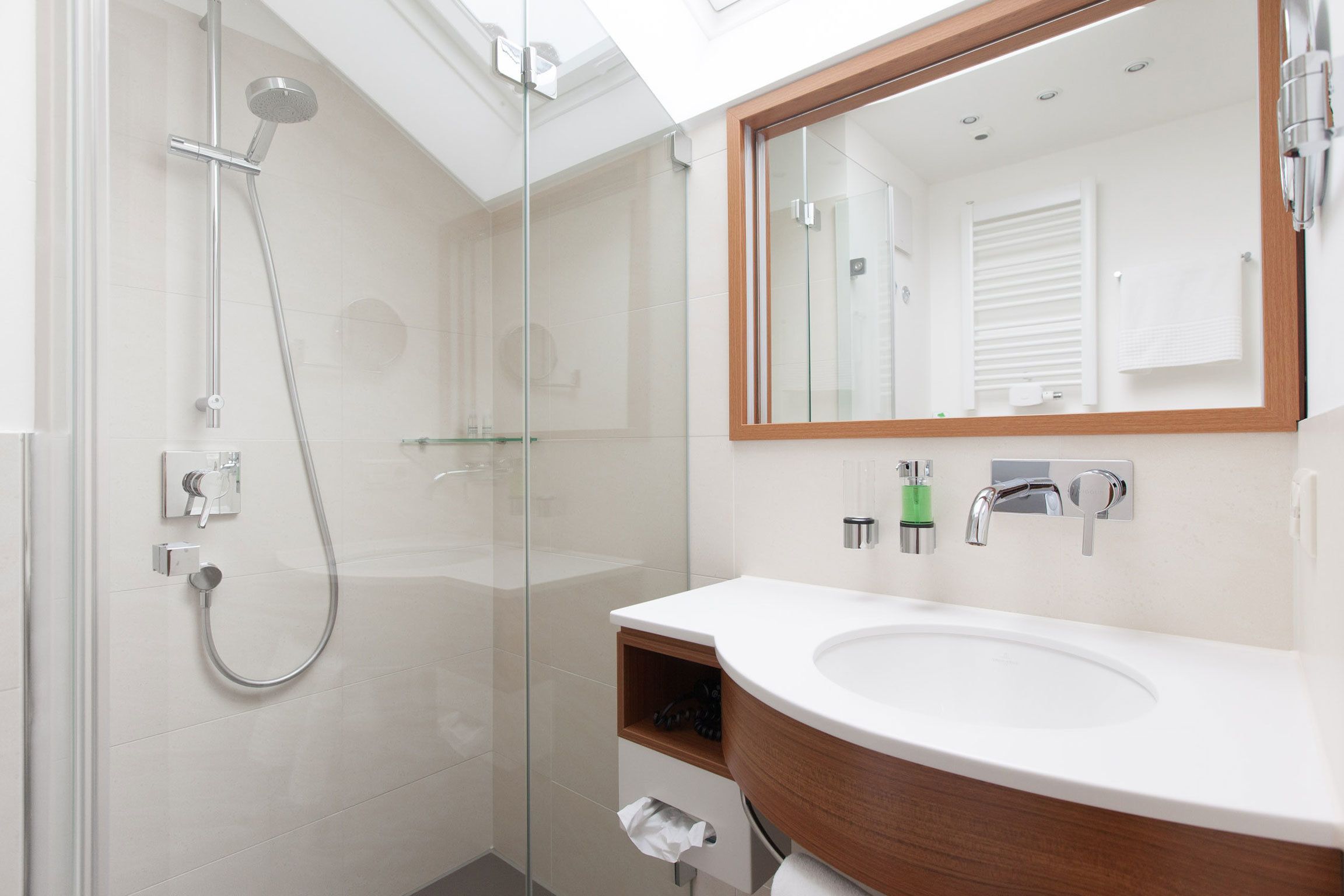 A modern bathroom with a glass-enclosed shower, a wooden vanity with a white sink, and a large mirror.