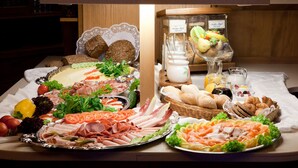 Un bufé con diversos alimentos, entre ellos carnes, quesos, frutas y pan.