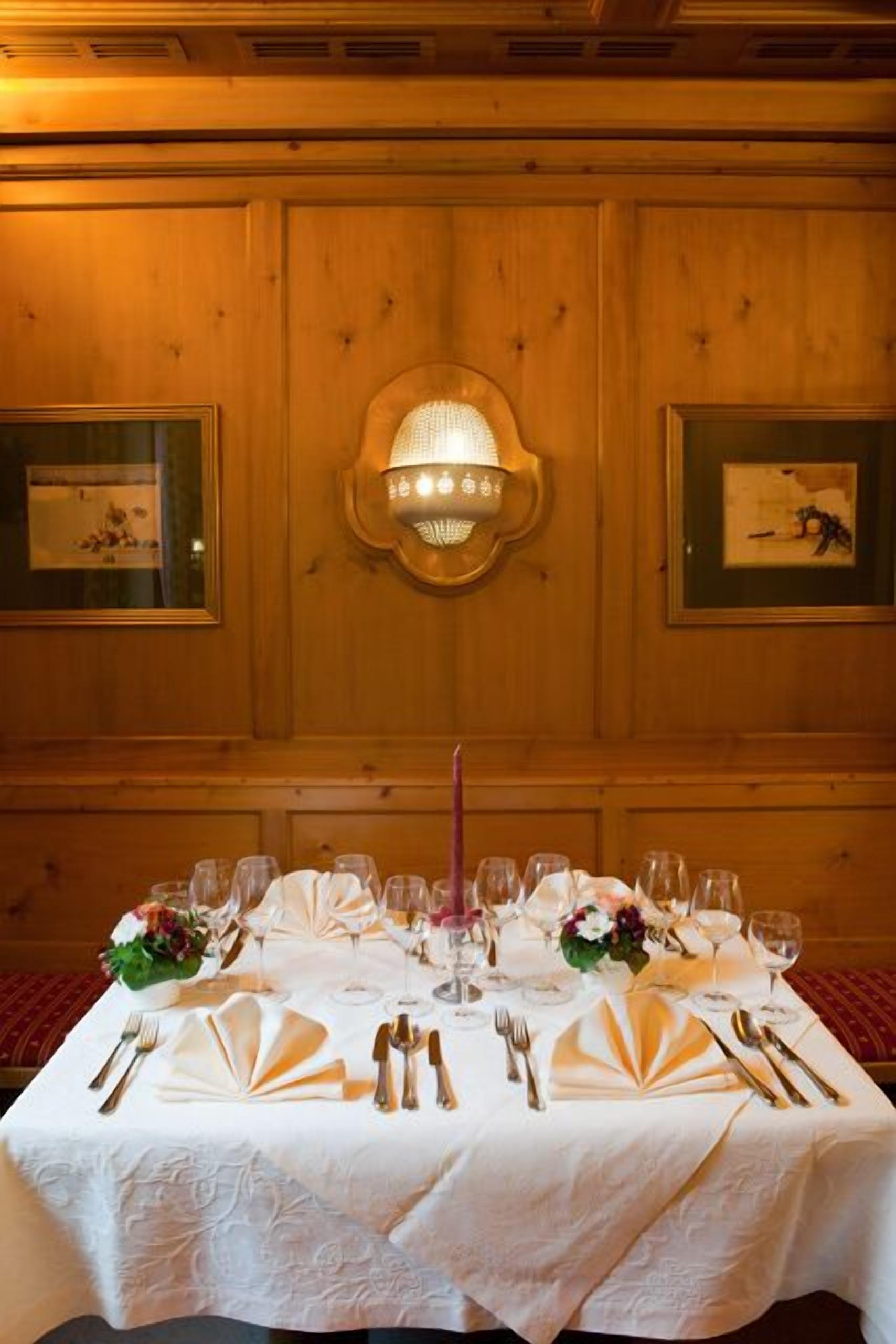 A dining table set with white tablecloth, gold cutlery, and a central candle.