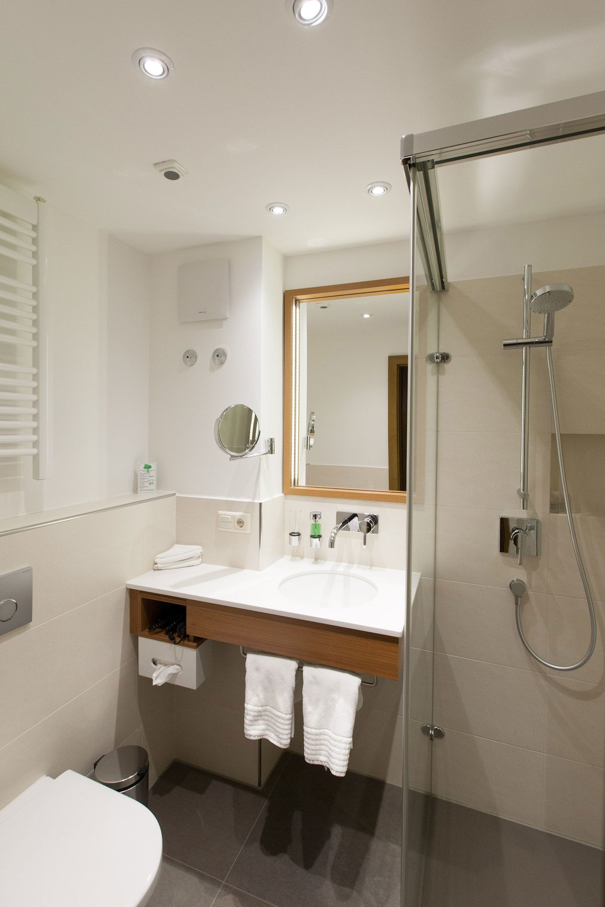 Une salle de bain moderne avec une douche à parois de verre, un lavabo blanc et un miroir au-dessus.