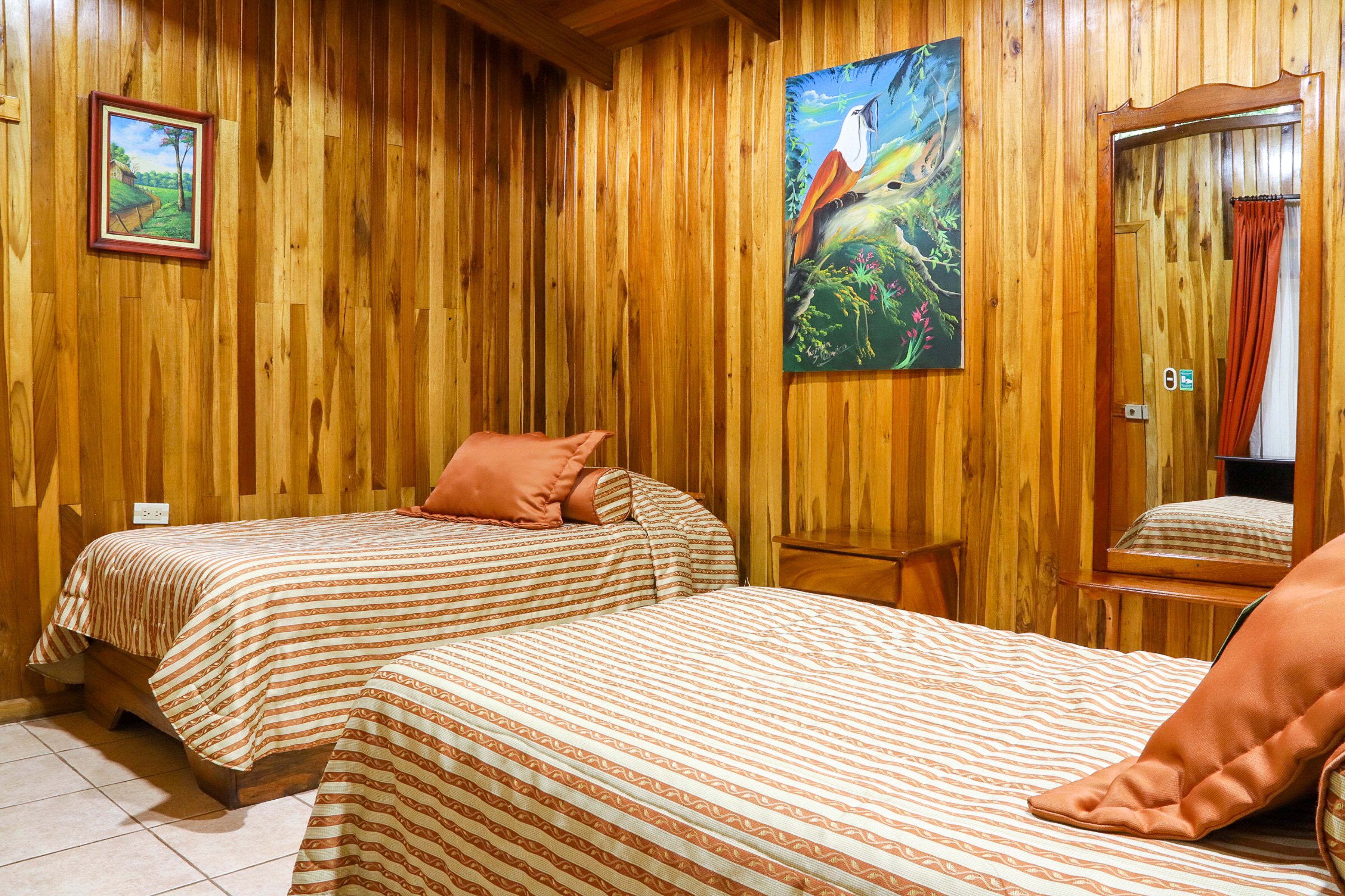 A wooden-paneled room with two beds, each with striped bedding.