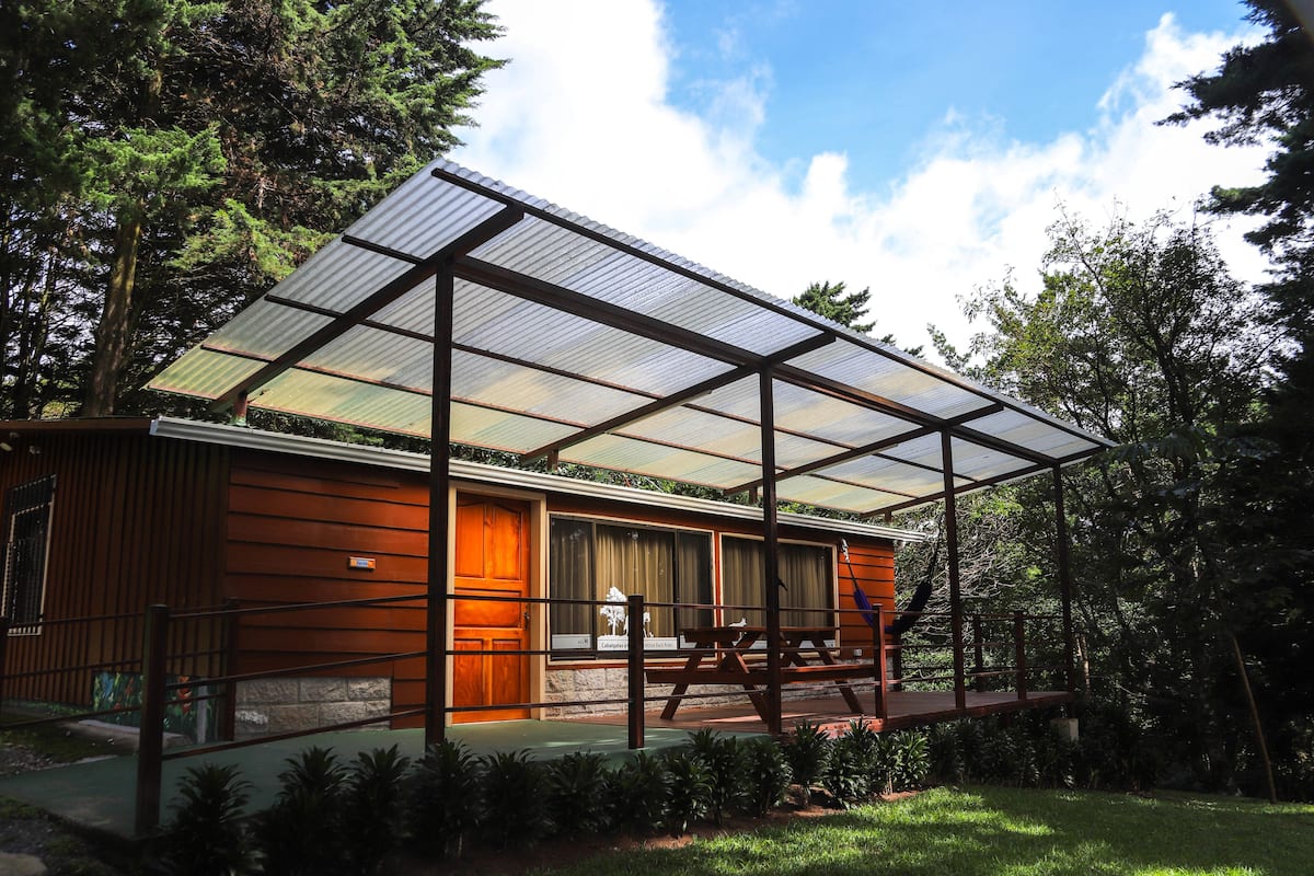 A modern house with a large glass extension, wooden exterior, and a covered patio.