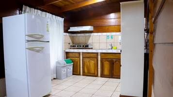 A kitchen with a white refrigerator, wooden cabinets, a tiled floor, and a built-in stove.