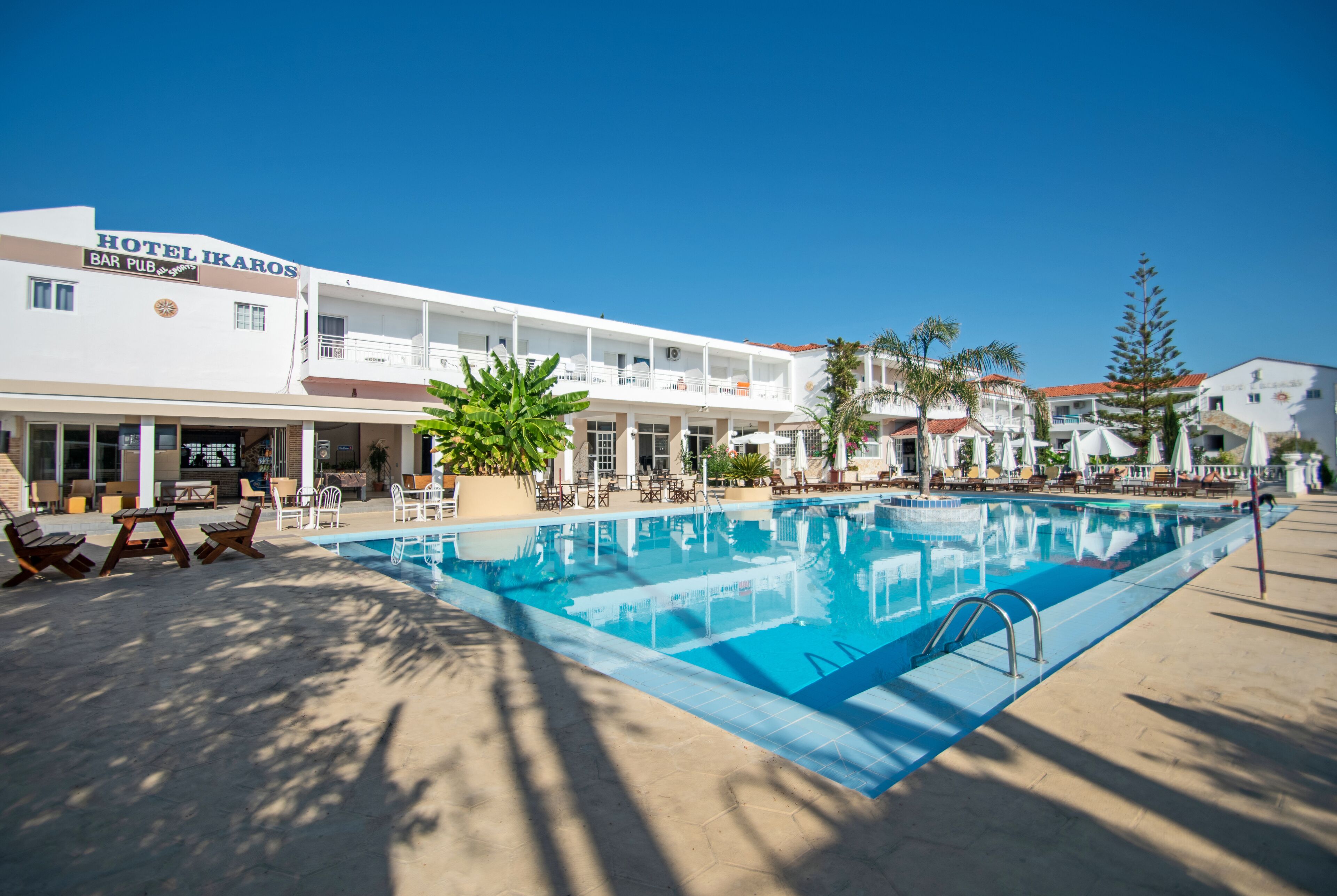 Un hotel con piscina, zona de estar al aire libre y bar.