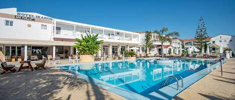 Un hotel con piscina, zona de estar al aire libre y bar.
