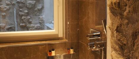 A bathroom with a stone wall, a bathtub, and a shower area.