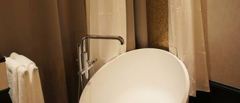 A modern bathroom with a freestanding bathtub, a shower curtain, and a towel rack.
