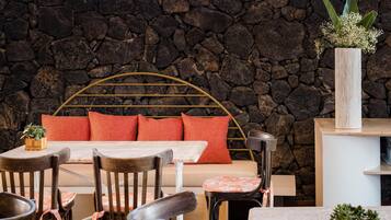 A cozy seating area with a stone wall backdrop, a wooden-framed bed, and a small table with chairs.