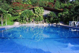 Una piscina al aire libre, sillones reclinables de piscina