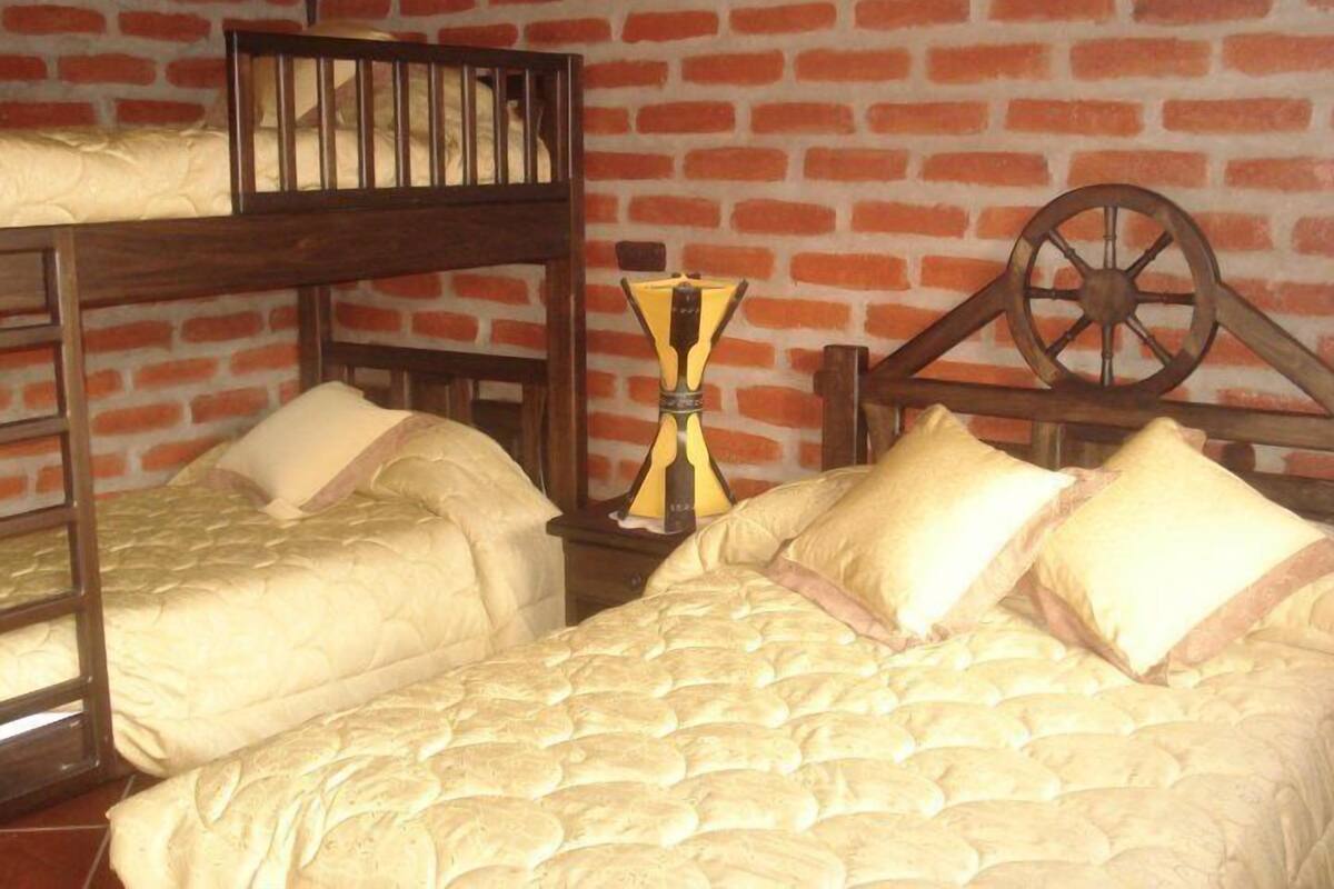 A room with two bunk beds, a wooden wheel, and a brick wall.
