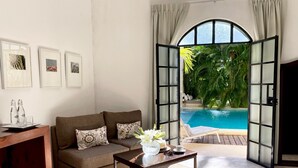 Una sala de estar con un sofá, una mesa de centro y vista a una piscina.