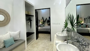 Un baño moderno con un espejo grande, un lavamanos redondo y una zona de ducha.