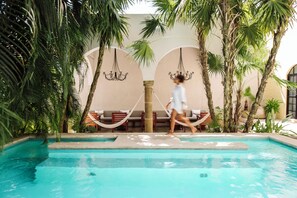A pool area with a clear view of the water, lounge chairs, and palm trees. - The Diplomat Boutique Hotel (Mérida)
