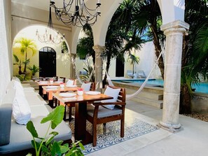 A dining area with tables and chairs, a pool, and tropical plants. - The Diplomat Boutique Hotel (Mérida)